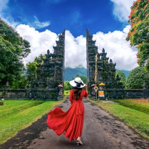 Woman walking at big entrance gate, Bali in Indonesia.