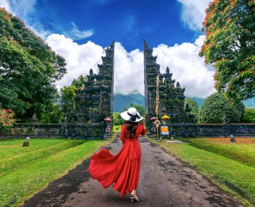 Woman walking at big entrance gate, Bali in Indonesia.